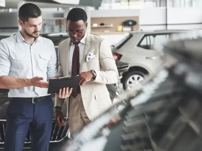 a-young-black-businesswoman-signs-documents-and-buys-a-new-car-the-car-dealer-is-standing-next-to.jpg
